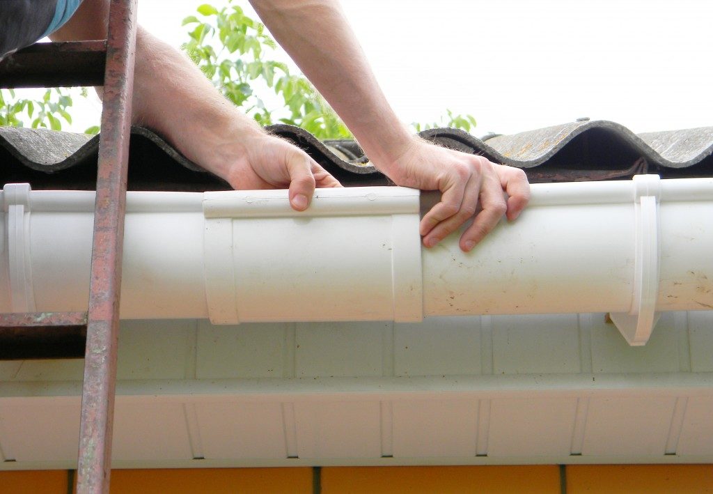 Man installing plastic roof gutter