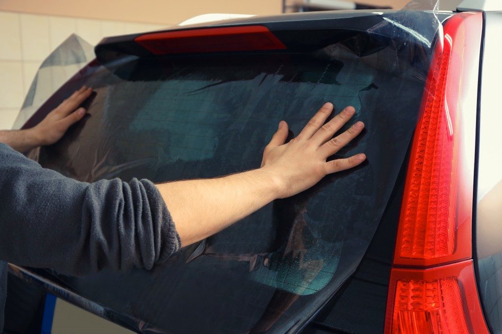 man tinting his car window
