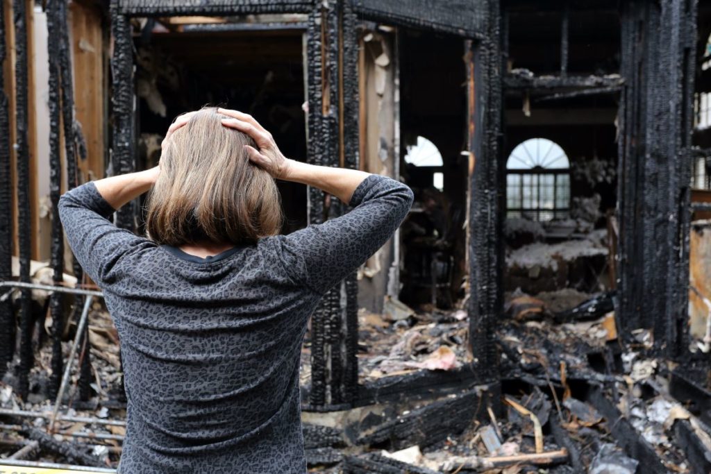 woman in shock in front of burnt down house