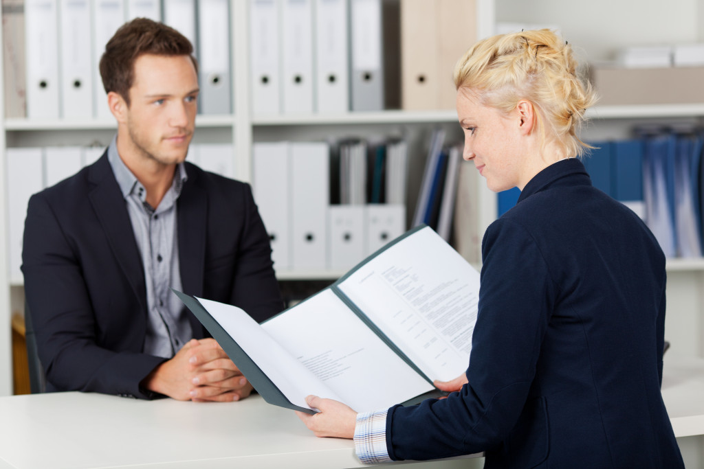 Female HR employee checking the records of a male office worker at work.