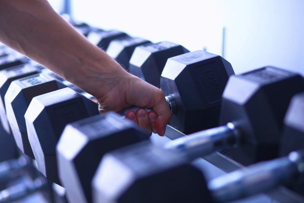 A person picking up a dumbbell from a rack in the gym
