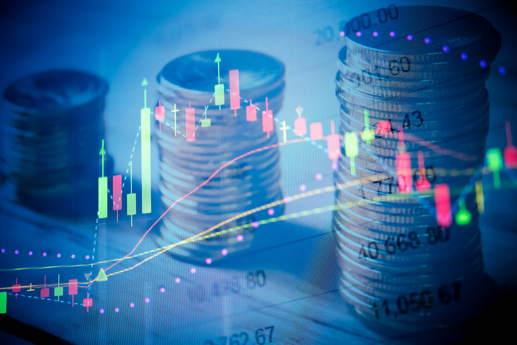 charts with different colors superimposed on a spreadsheet and stacks of coins