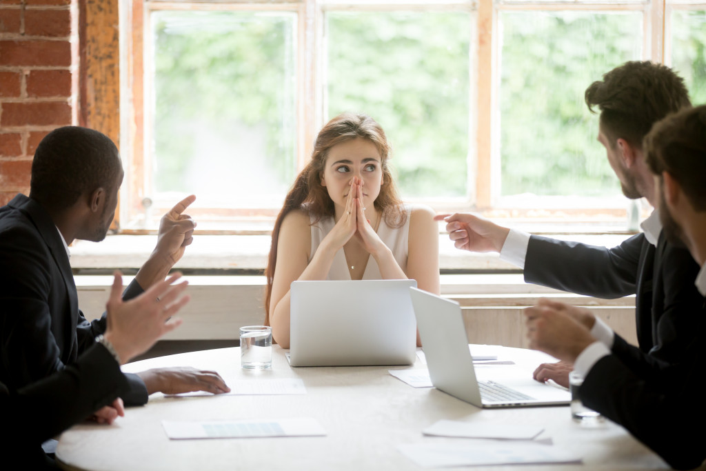 workplace conflict between men with woman in the middle