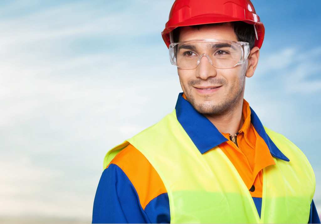 A man wearing a hard hat, safety goggles, and a reflective jacket